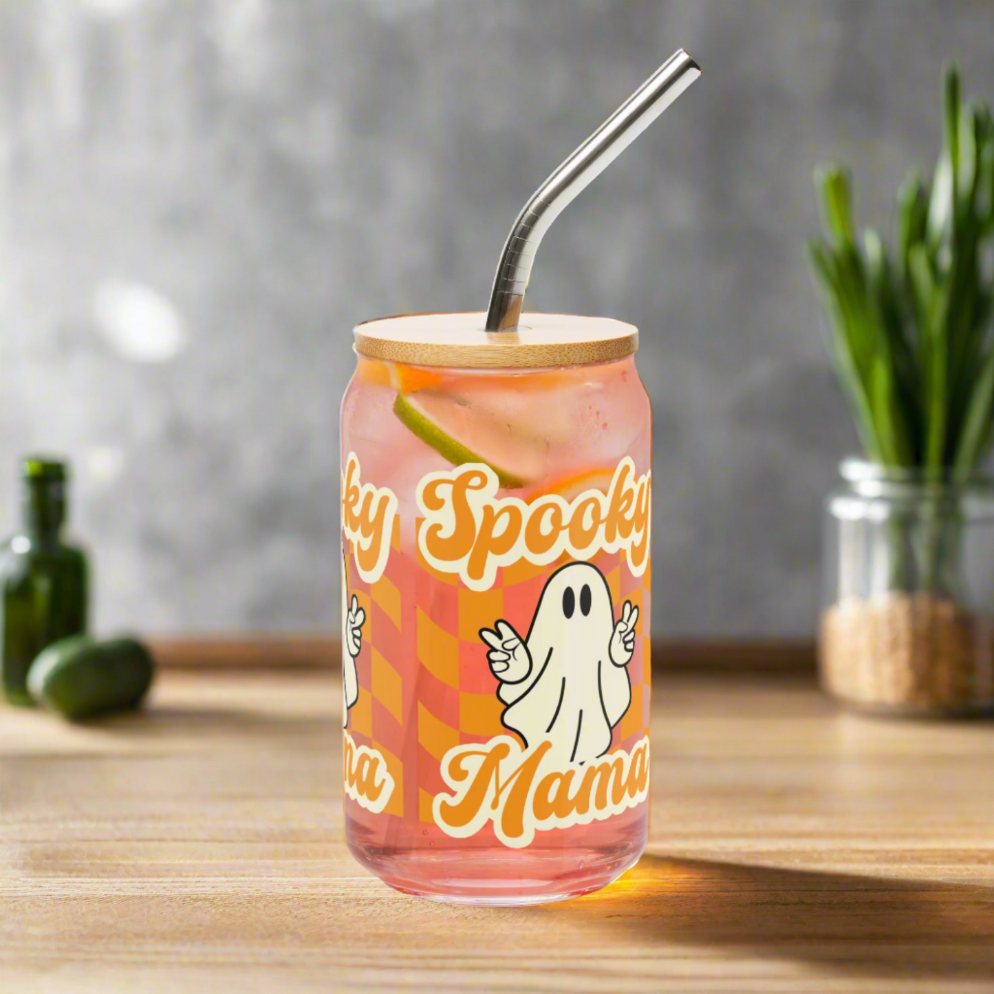 Spooky Mama glass tumbler with bamboo lid and straw for iced coffee, cold brew, or cocktails. Halloween drinkware with cute ghost artwork and orange checkerboard design. Sustainable 16 oz reusable glass cup that makes a charming Halloween gift for mom, girlfriend, or coffee lover. Perfect addition to your fall drink collection.