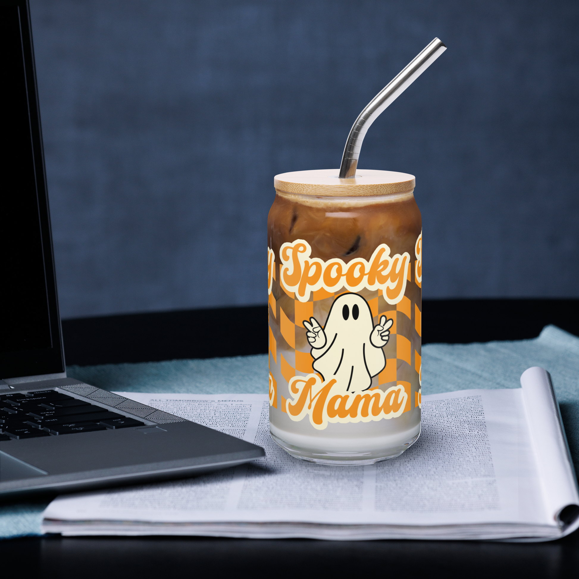 Cute Ghost Halloween Fall 16 oz Sipper Glass Funny Halloween Gift for Mom Spooky Mama Halloween Glass Coffee Cup, featuring a orange checkerboard design with a white ghost giving the peace sign and the text Spooky Mama in orange and white cursive bubble font by jaecrece.com