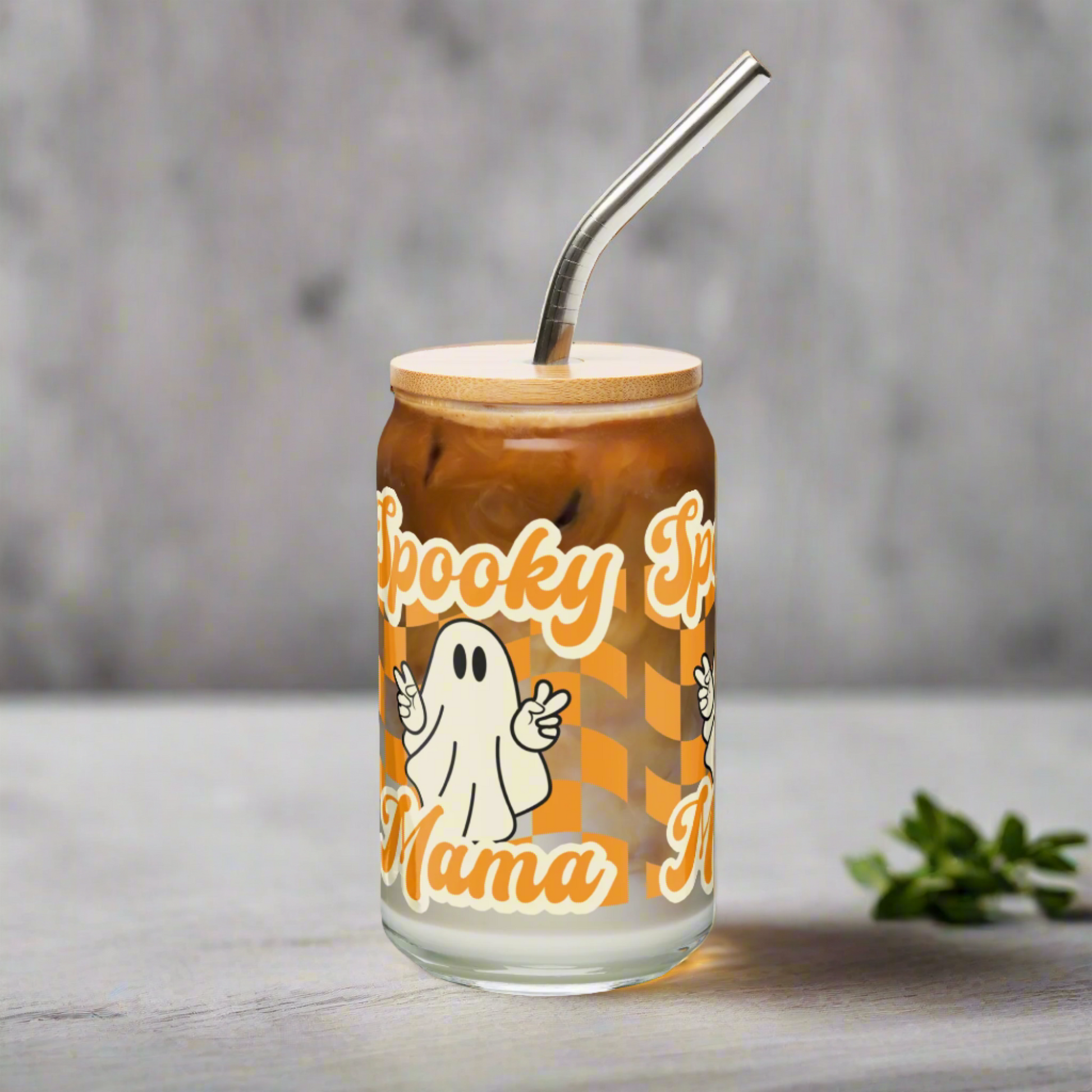 Celebrate spooky season with this Spooky Mama iced coffee glass, 16 oz tumbler with bamboo lid and straw. Features ghost illustration and orange checkerboard design for festive fall flair. Ideal Halloween gift for her, iced coffee lovers gift, or seasonal home drinkware accessory. Eco friendly, reusable, and fun for any Halloween party.