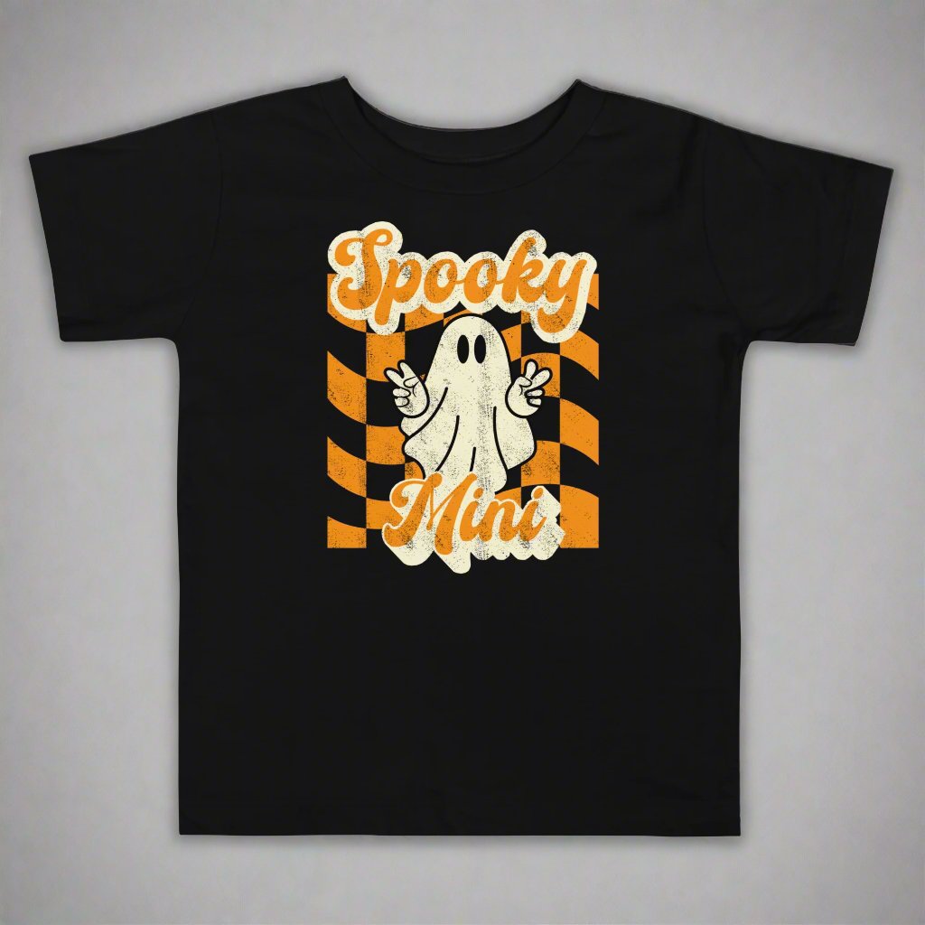  Spooky Mini Halloween Toddler Shirt  featuring an orange checkerboard pattern with a cute ghost graphic. The text reads Spooky Mini, by jaecrece