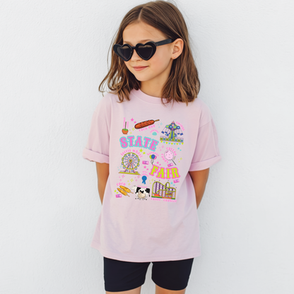 Youth State Fair graphic T shirt featuring colorful carnival and county fair artwork with Ferris wheel, roller coaster, swing ride, cotton candy, funnel cake, corn dogs, balloons, livestock and blue ribbon illustrations. Retro lettering and bright colors create a playful fair day look for kids.

