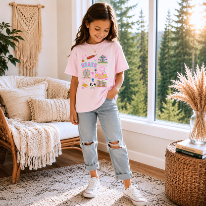 Kids State Fair shirt in a retro Americana style featuring colorful Ferris wheel and roller coaster artwork along with cotton candy, funnel cake, corn dogs, balloons, livestock, blue ribbon and fair tickets. Bright pink, aqua, lime, orange and purple details create a cheerful summer graphic for fair season.