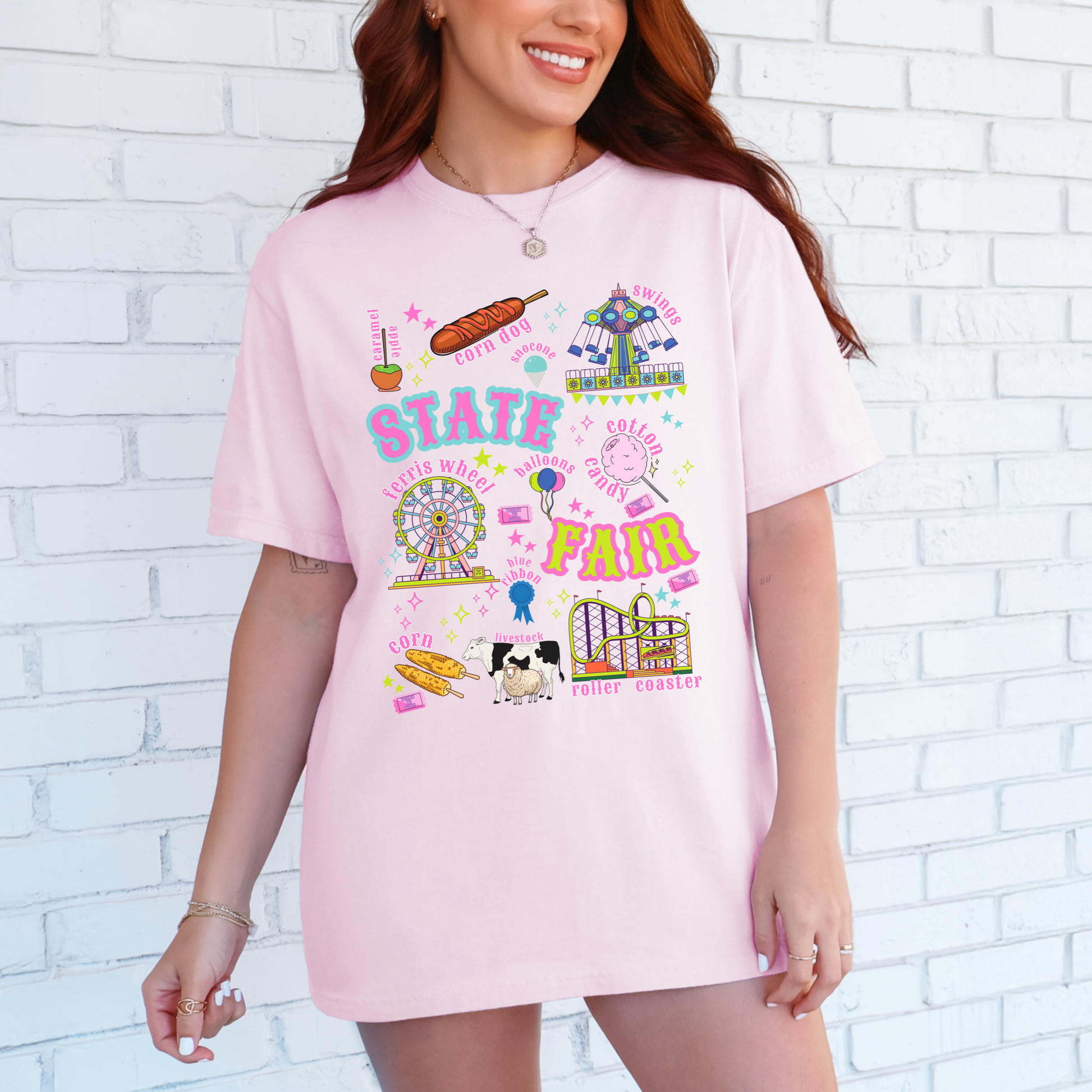 Blossom pink Comfort Colors 1717 T shirt featuring a colorful retro State Fair and County Fair graphic with Ferris wheel, roller coaster, carnival ride, cotton candy, funnel cake, corn dogs, balloons, livestock, blue ribbon and fair tickets, creating a playful vintage Americana look for summer fairs and festivals.
