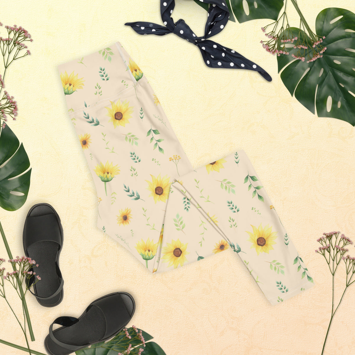 Detailed view of the floral pattern on sunflower women's leggings, showing different sizes of yellow sunflowers mixed with green leaves, small branches, and delicate botanical sprigs. The flowers have an illustrated appearance that gives the design a soft vintage garden aesthetic. The cream background keeps the pattern light and versatile, making these leggings easy to pair with neutral tops and other casual wardrobe pieces.
