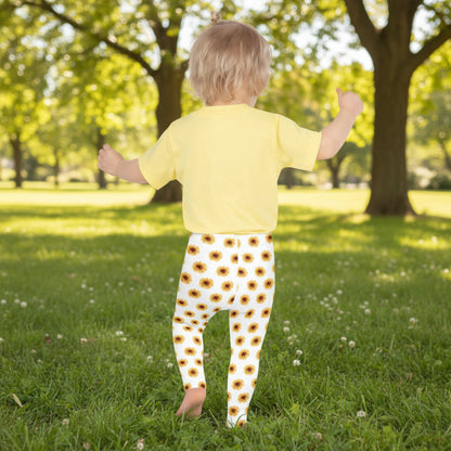 These sunflower print toddler leggings feature a vibrant yellow floral design on soft white fabric. Ideal for playdates, school, or lounging, the full-length fit and high-rise waist offer all-day comfort. Made from smooth microfiber that stays bright and flexible, they’re perfect for little girls who love sunshine and flowers. Part of a matching family sunflower set for coordinated looks with mom or siblings.