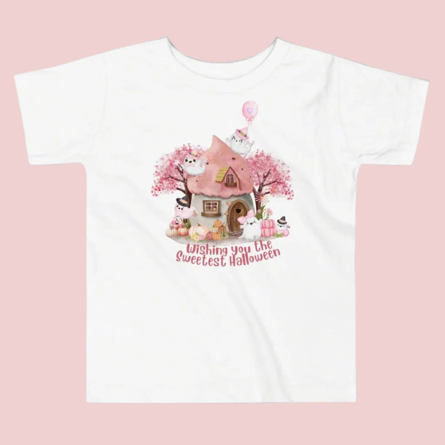 Pink toddler tshirt with a storybook cottage, pink trees, pink pumpkins and five sweet ghosts. The text reads Wishing you the sweetest halloween, by jaecrece