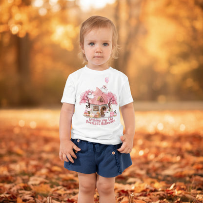 Cute Halloween toddler tee design featuring pink and white ghosts, pastel pumpkins, colorful flowers, and a tiny haunted cottage surrounded by autumn trees. Wishing You the Sweetest Halloween appears below the illustration in playful pink lettering.