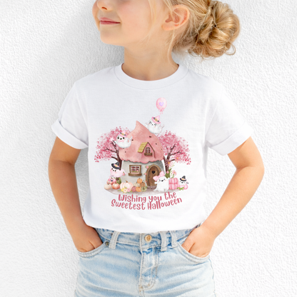 Sweet pink Halloween toddler shirt featuring adorable watercolor ghosts wearing Halloween hats, pink pumpkins, flowers, and a charming haunted cottage with the words Wishing You the Sweetest Halloween. Cute festive design for toddlers who love a softer, more whimsical Halloween style.