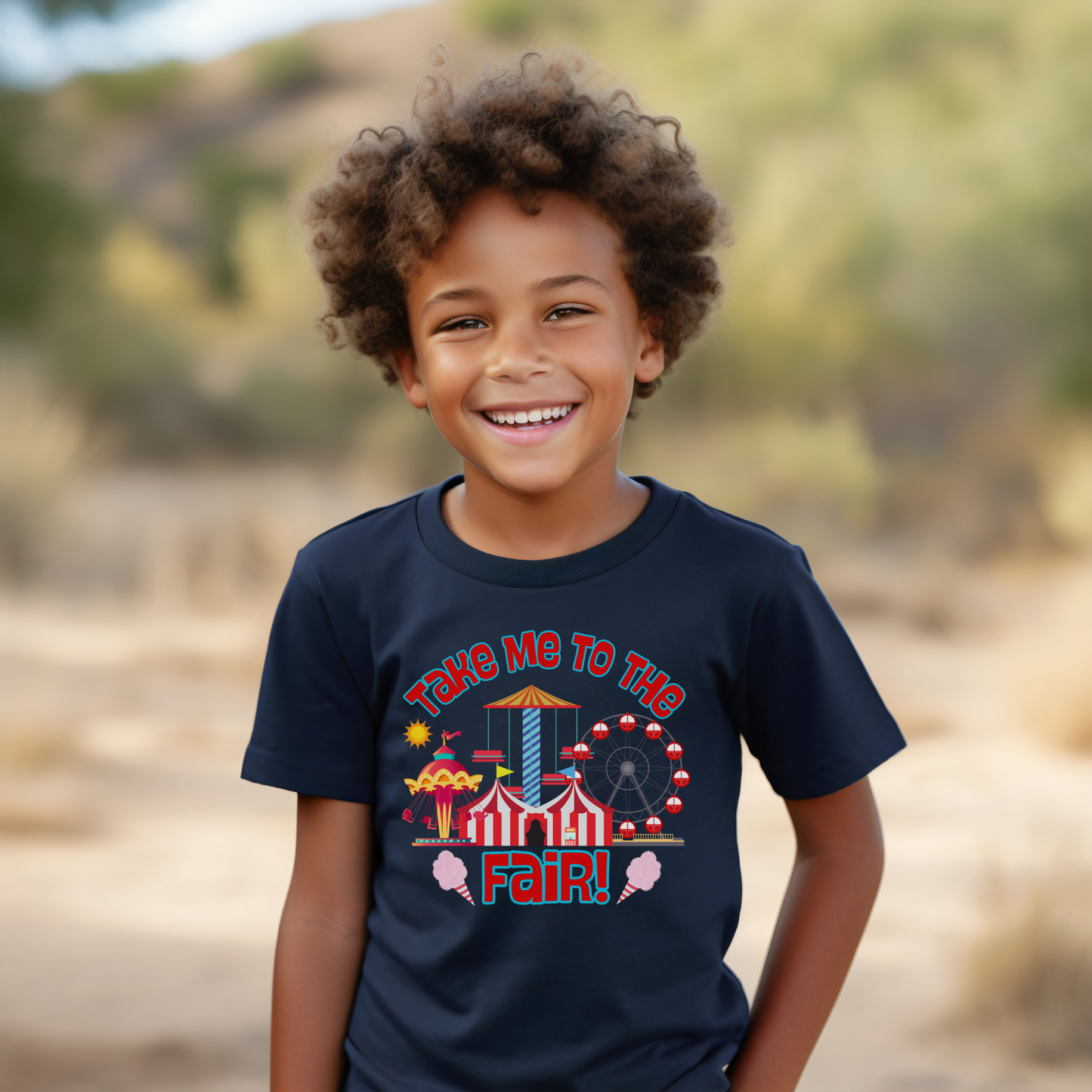 Young boy wearing a Crewneck tee that reads take me to the fair with a fairground graphic of rides and cotton candy