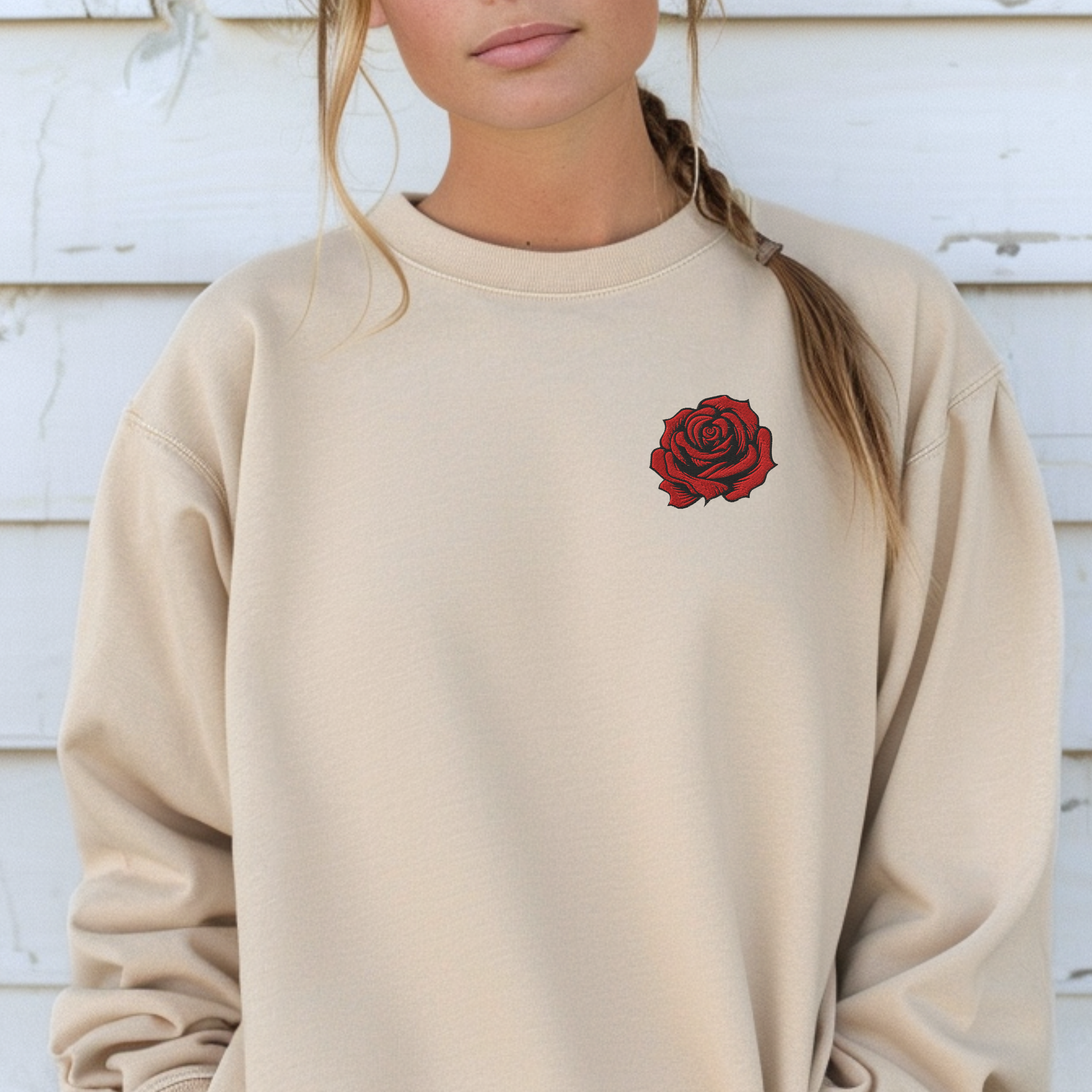 Woman wearing a Sand embroidered rose sweatshirt featuring bold red floral embroidery on the chest. The soft cotton polyester blend sweatshirt offers a cozy classic fit with durable stitching, perfect for casual everyday wear, lounging, or layering. Ideal as a June birth flower gift, birthday present, anniversary gift, or Valentine’s Day surprise for women who love romantic floral embroidery and timeless style.