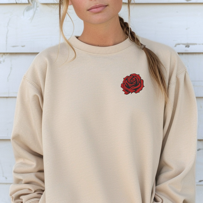 Woman wearing a Sand embroidered rose sweatshirt featuring bold red floral embroidery on the chest. The soft cotton polyester blend sweatshirt offers a cozy classic fit with durable stitching, perfect for casual everyday wear, lounging, or layering. Ideal as a June birth flower gift, birthday present, anniversary gift, or Valentine’s Day surprise for women who love romantic floral embroidery and timeless style.