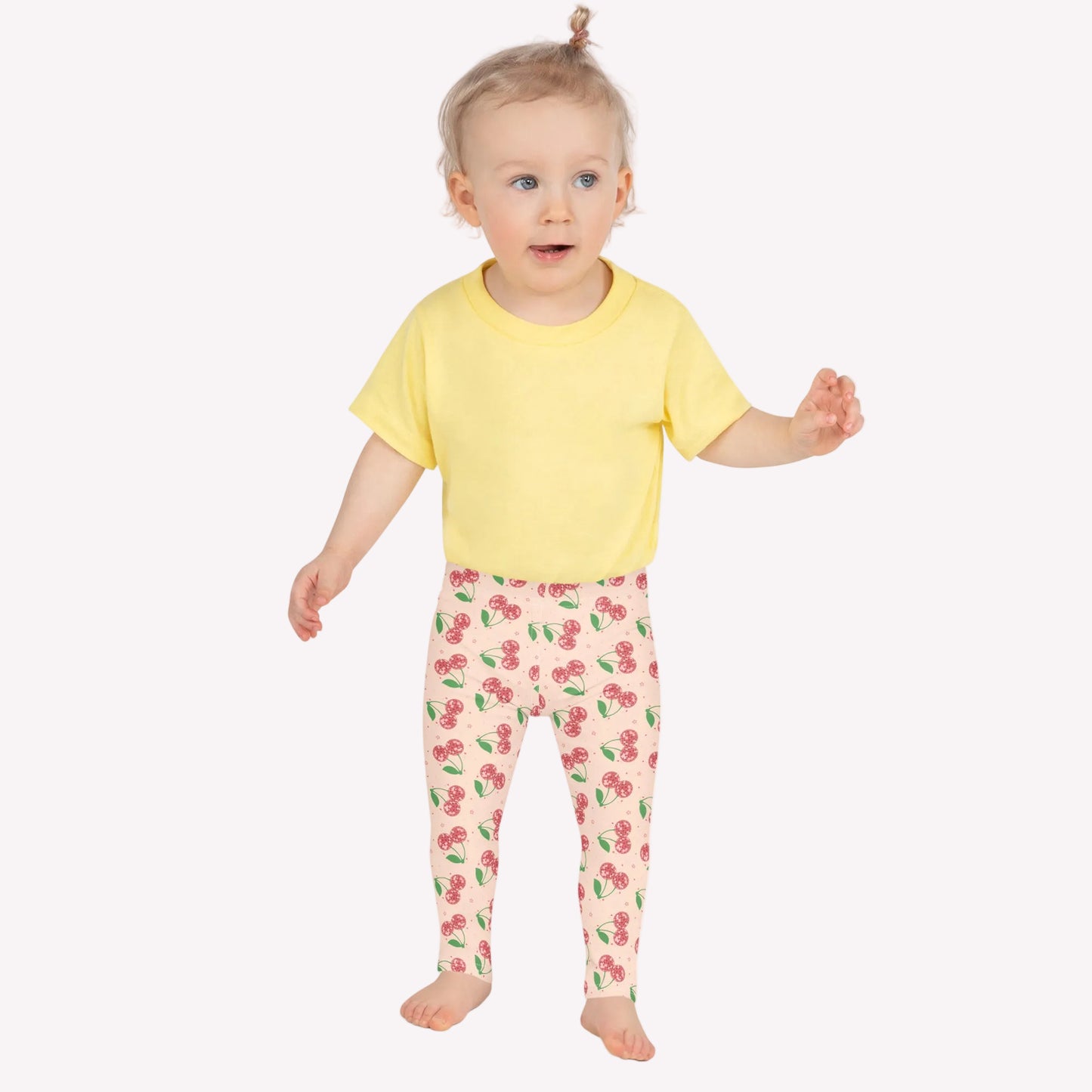 Girls cherry leggings with a light pink base and bright red cherry print, designed in a full length silhouette with a secure high rise waistband. These leggings for kids provide comfortable stretch for movement, making them perfect for activewear, school days, dance class, or casual outfits. A sweet fruit inspired design that blends everyday comfort with a playful and trendy aesthetic for girls clothing collections.