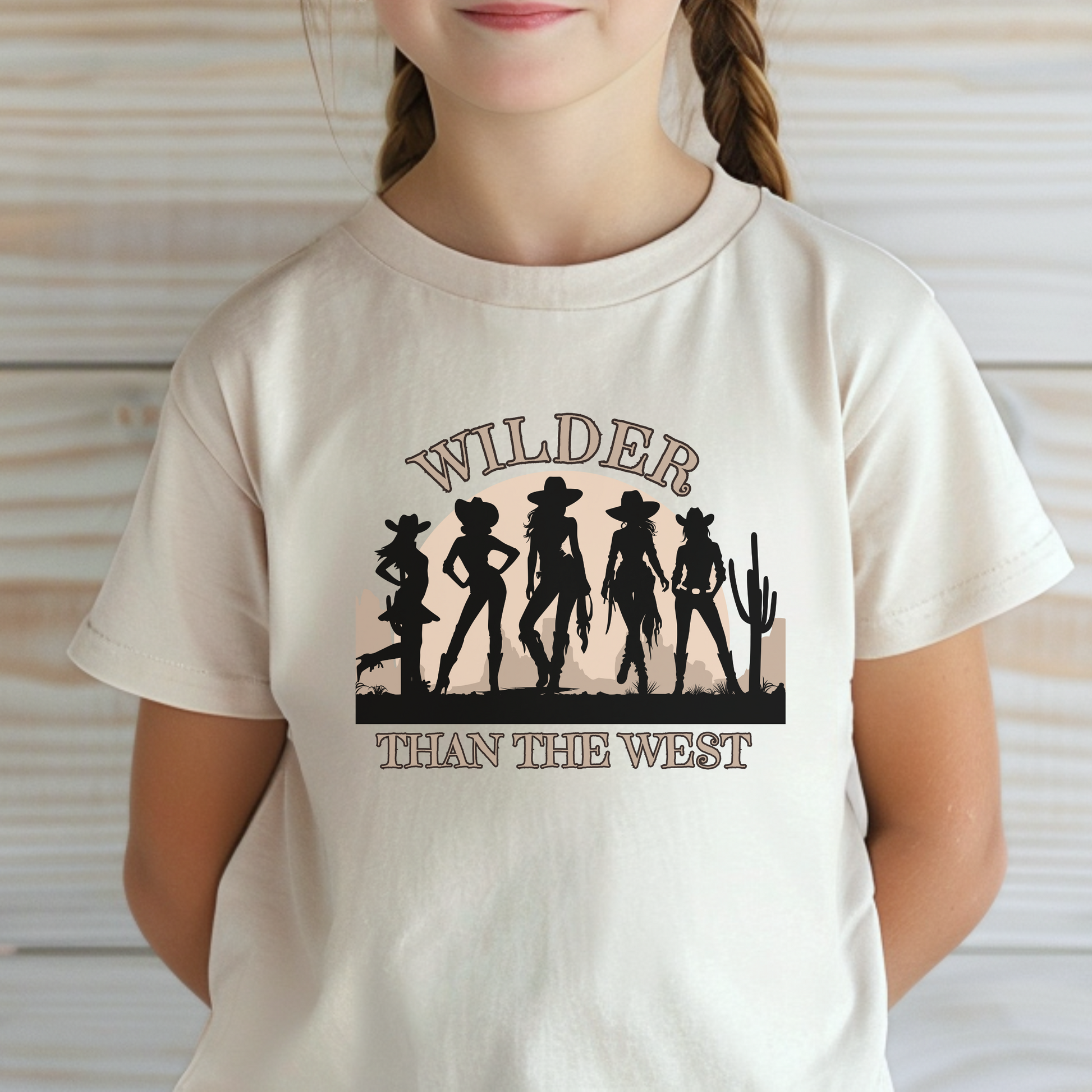 This toddler cowgirl graphic tee features bold western silhouettes of five cowgirls with a cactus and sunset background and the phrase “Wilder than the West.” A perfect toddler western quote tee for rodeo birthday parties, desert-themed festivals, or country fair adventures. Soft, lightweight, and perfect for matching mommy and me cowgirl outfits. Great choice for mini southern girls with a state Texas coquette aesthetic.