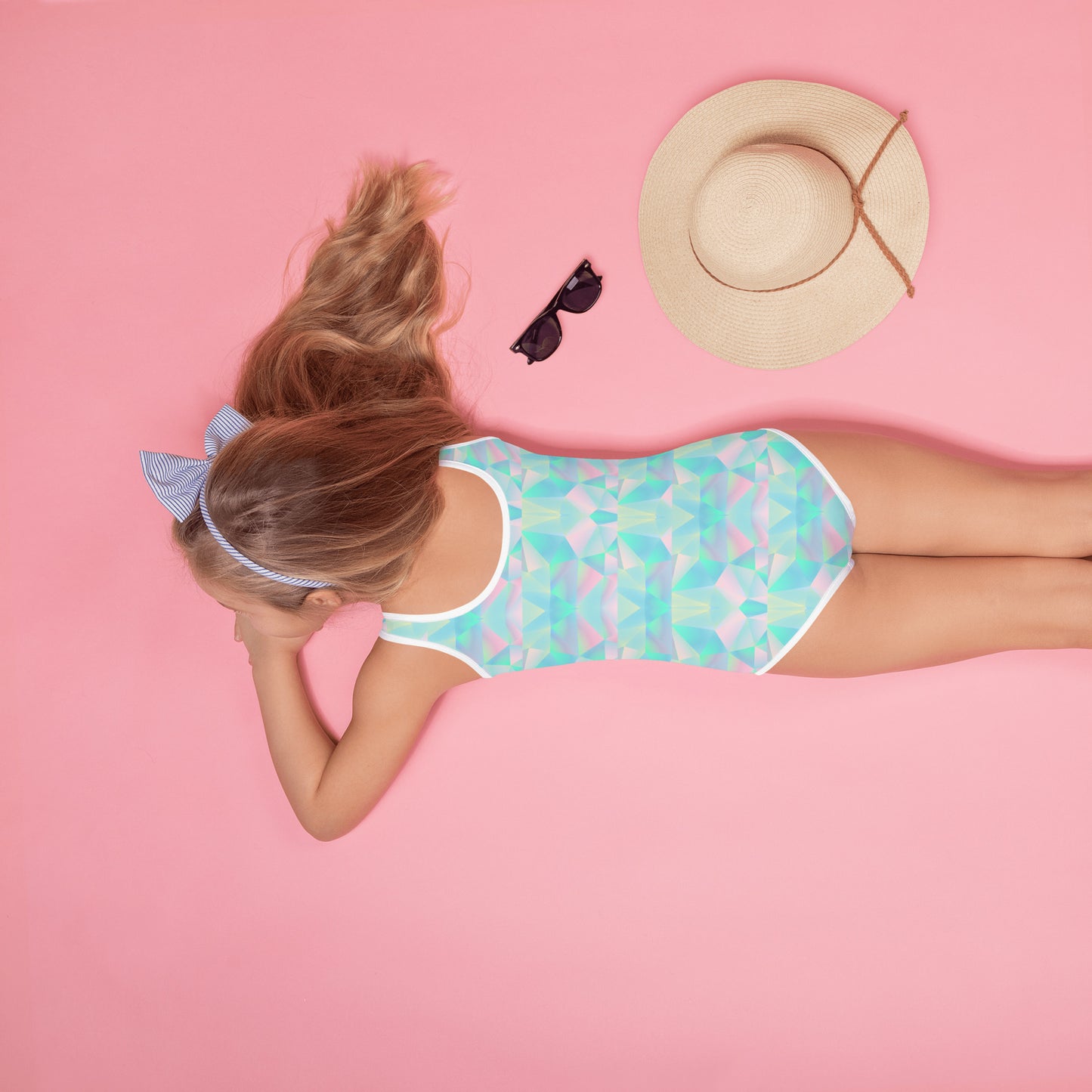 This colorful girls bathing suit features an eye catching prism design with shades of teal blue, pink, and purple that blend into a playful retro aesthetic. Available in sizes 2T through 20, it allows toddlers through teens to join in on matching family memories. A wonderful choice for family cruises, tropical vacations, poolside celebrations, birthday surprises, summer camp packing, and coordinated vacation outfits.