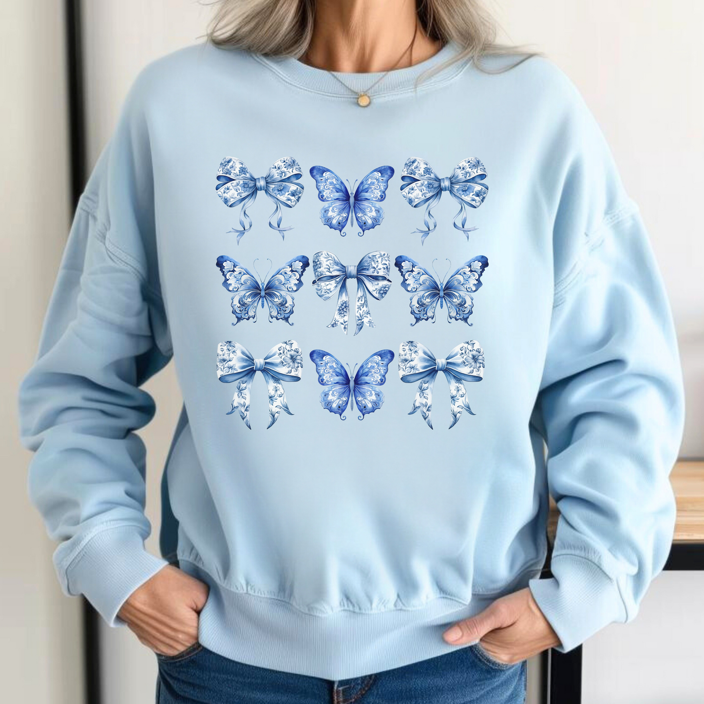 Image: Soft and stylish women's sweatshirt featuring blue toile butterfly and bow graphics, inspired by coastal cowgirl trends and Texas springtime flair. A comfy statement piece for moms, this top is perfect for coordinating mommy and me outfits and weekend wear. Pair with jeans or leggings and match with toddler or girls’ designs for a complete family ensemble, by jaecrece.