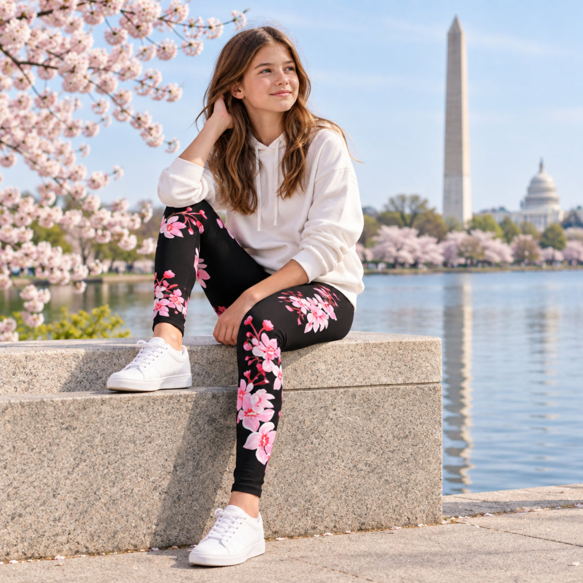Young girl wearing black full length leggings with a delicate pink Japanese cherry blossom pattern while walking along a sidewalk in Washington DC. The high rise sakura leggings create a pretty spring outfit for sightseeing, walking, family trips, travel, outdoor activities, and enjoying cherry blossom season in Washington DC.