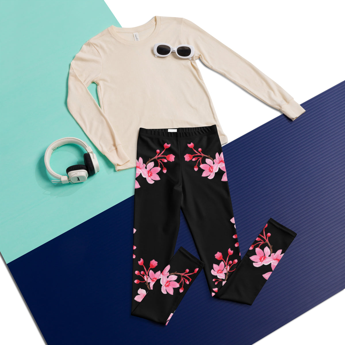 Flatlay of black cherry blossom leggings featuring delicate pink sakura flowers and graceful flowering branches, highlighting the full length design and feminine Japanese inspired floral pattern. These high rise leggings are designed for tween and teen girls and can be styled as everyday leggings or yoga pants with casual tops, sweatshirts, sweaters, and spring outfits.