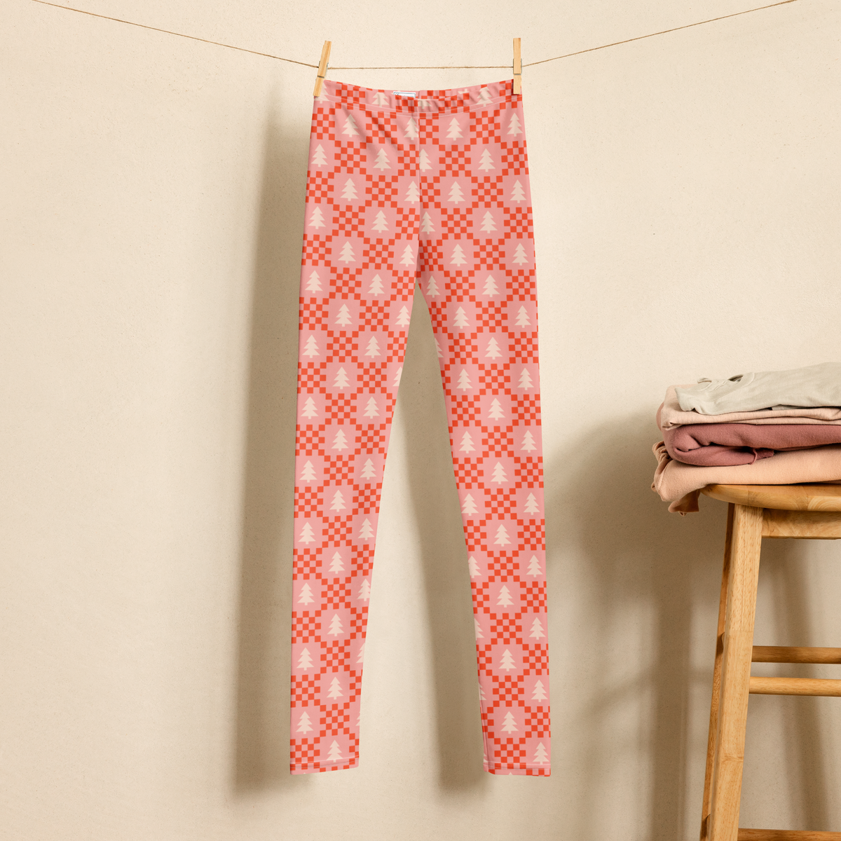 Pink Christmas leggings designed for girls, tweens, and teens, featuring cream evergreen trees and red geometric details on a soft pink background. The playful pattern offers a stylish alternative to traditional red and green holiday clothing and works for Christmas parties, school events, family photos, holiday shopping, or casual winter outfits. Sizes 2T through 20 make it easier to find the same festive style across different ages.
