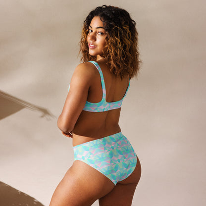 Image: This high waist two piece bathing suit features a pastel prism pattern in soft shades of teal, blue, and pink, creating a dreamy geometric design. Made from recycled materials, this swimsuit offers both style and sustainability. The high-waisted bottom provides comfort and coverage, while the top ensures support, making it a perfect choice for poolside lounging, tropical vacations, or beach outings, by jaecrece.