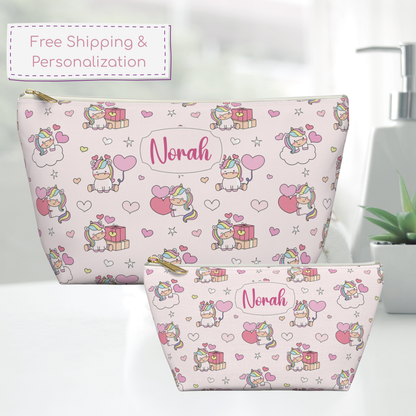 Small and large personalized unicorn zipper pouches sit side by side on a counter, showing the difference in size and the pastel rainbow design. The whimsical cutecore aesthetic features colorful unicorns, hearts, stars, clouds and gift details. These cute girls accessories can be used as a makeup bag, toiletry pouch, travel organizer or everyday storage bag.