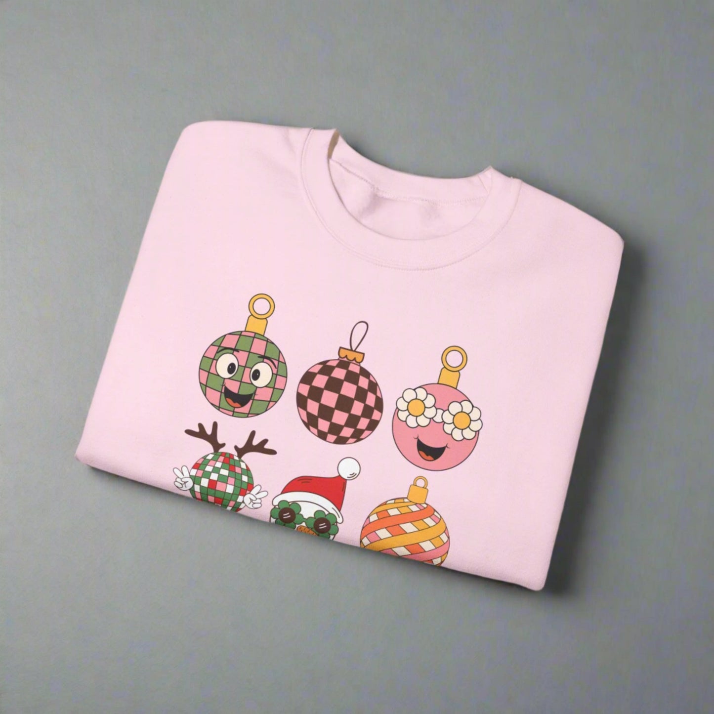 Retro holiday sweatshirt with nine colorful ornament designs, including flowers, checkered patterns, and a retro Santa with sunglasses. This fun Christmas crewneck is printed on Gildan 18000 and comes in light pink, black, or sand. Available in sizes S–5XL, it makes a playful Christmas party outfit, vintage holiday wardrobe staple, or retro Christmas gift. Cozy and unisex, this festive pullover is perfect for spreading cheerful and groovy holiday vibes.