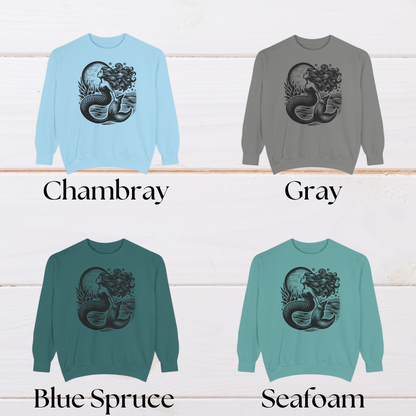 Comfort Colors 1566 sweatshirt featuring a vintage-style mermaid design in black ink. Shown in a flat lay, this ocean graphic pullover is available in Blue Spruce, Chambray, Grey, and Seafoam, sizes small through 3XL. With a soft cotton blend and relaxed fit, this whimsical sweatshirt makes a thoughtful gift for beach lovers, women, and teens who adore nautical fashion, cozy coastal wear, or fantasy-inspired clothing.