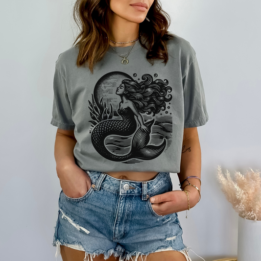 Image: Vintage Nautical Mermaid T-shirt printed on a Comfort Colors soft-washed tee, featuring a retro mermaid illustration inspired by antique maritime art. This beach-ready shirt blends mermaidcore style with vintage nautical aesthetics, making it a must-have for ocean lovers, soft girl summer outfits, and coastal cowgirl fashion. A perfect gift for beach lovers or fans of whimsical, ocean-themed apparel. Includes free U.S. shipping, by jaecrece.