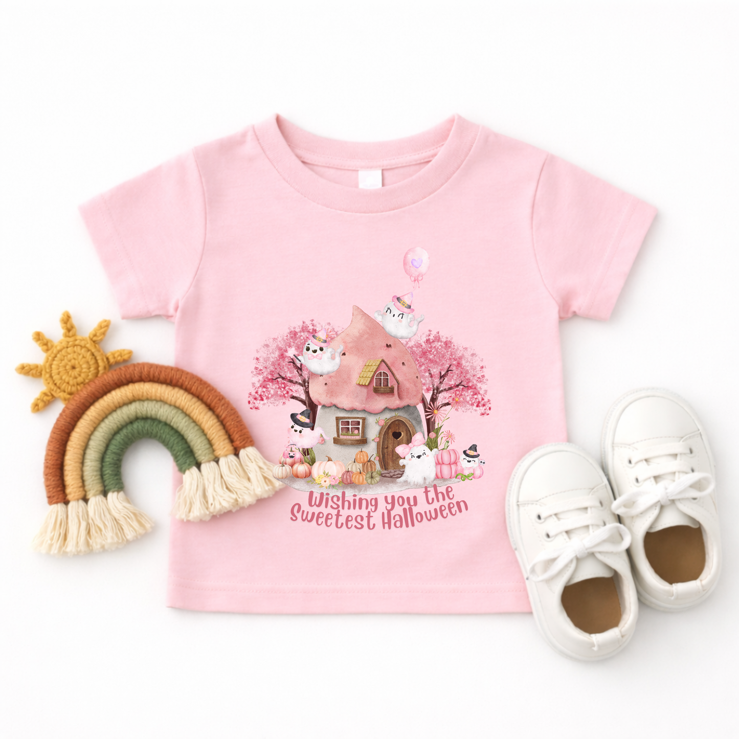 Sweet pink Halloween featuring cute ghost characters in Halloween hats surrounded by pumpkins, flowers, trees, and a whimsical cottage. The phrase Wishing You the Sweetest Halloween adds a playful finishing touch to this feminine and colorful toddler Halloween shirt design.