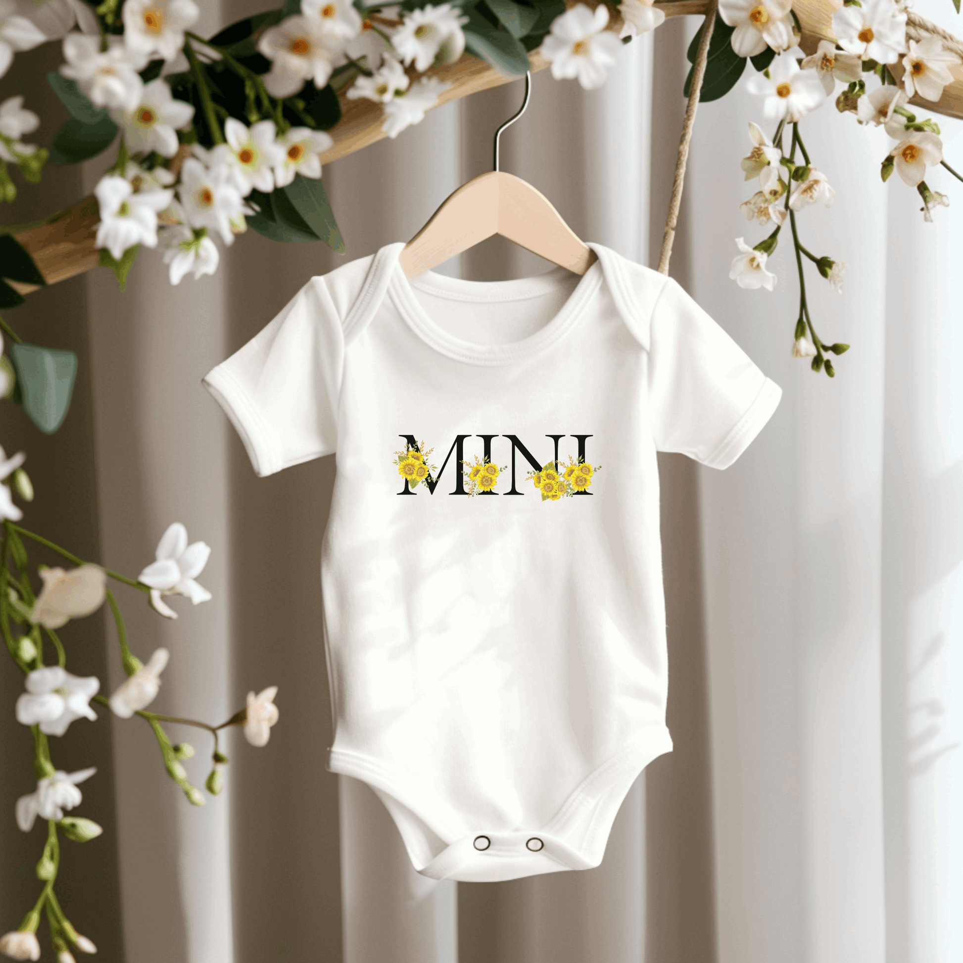 Dress your little one in a Mini Sunflower Baby Bodysuit in White or Pink, crafted from soft Bella Canvas 100B fabric. Featuring “MINI” sunflower calligraphy, this baby bodysuit coordinates perfectly with the matching MAMA sweatshirt or tee for family photos, special occasions, or everyday fun. Lightweight, breathable, and easy to wear, it’s a cozy, cute, and practical addition to soft baby clothes collections.