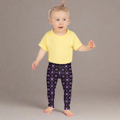 Wickedly Cute Toddler & Kids Halloween Leggings, featuring a black material with a purple geometric pattern that consists of spiders webs, pumpkins, witches hats and skulls, by jaecrece.com