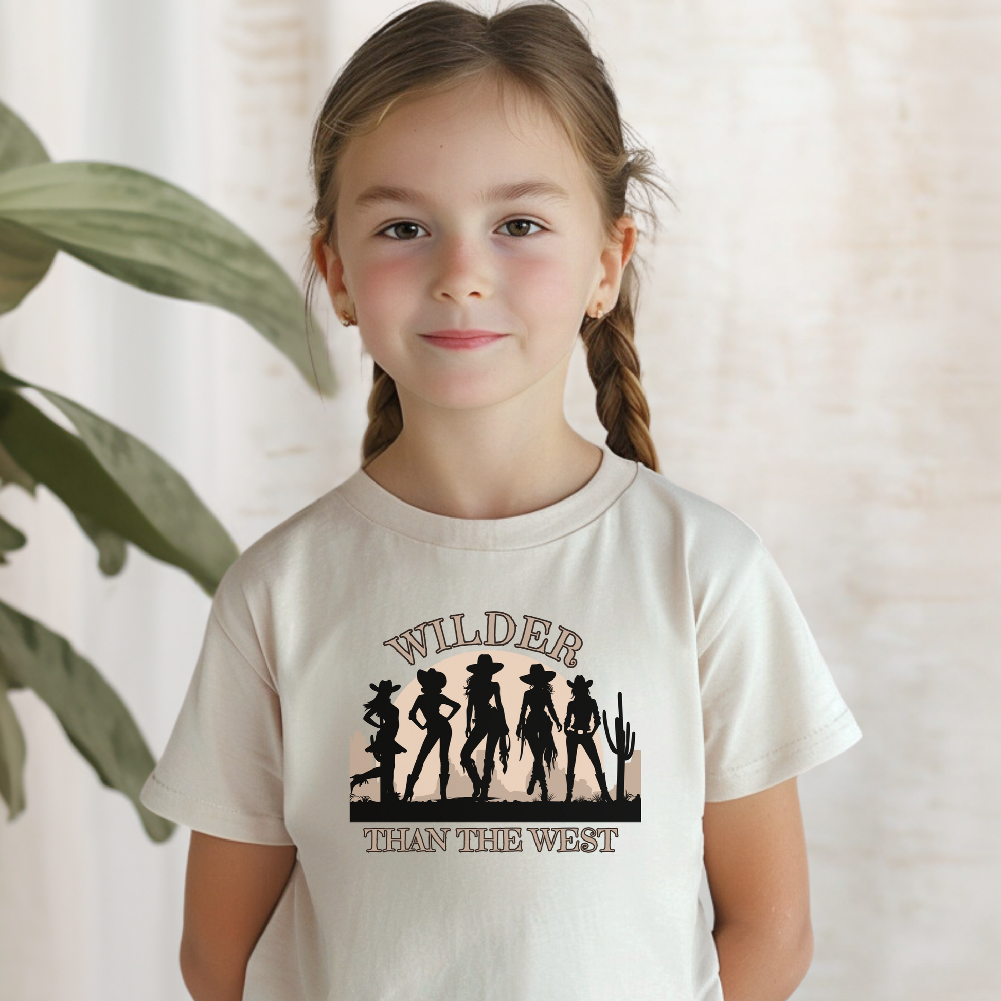 Toddler western tee in soft natural features five bold cowgirl silhouettes, desert cactus, and sunset with the slogan “Wilder than the West.” Designed for southern mini cowgirls, this toddler graphic shirt pairs with women’s and girls’ tees for a fun mama and mini matching outfit. Ideal for rodeos, bachelorette trips, country music festivals, or casual Texas state fairwear. Adds a playful vibe to toddler desert-themed wardrobes.
