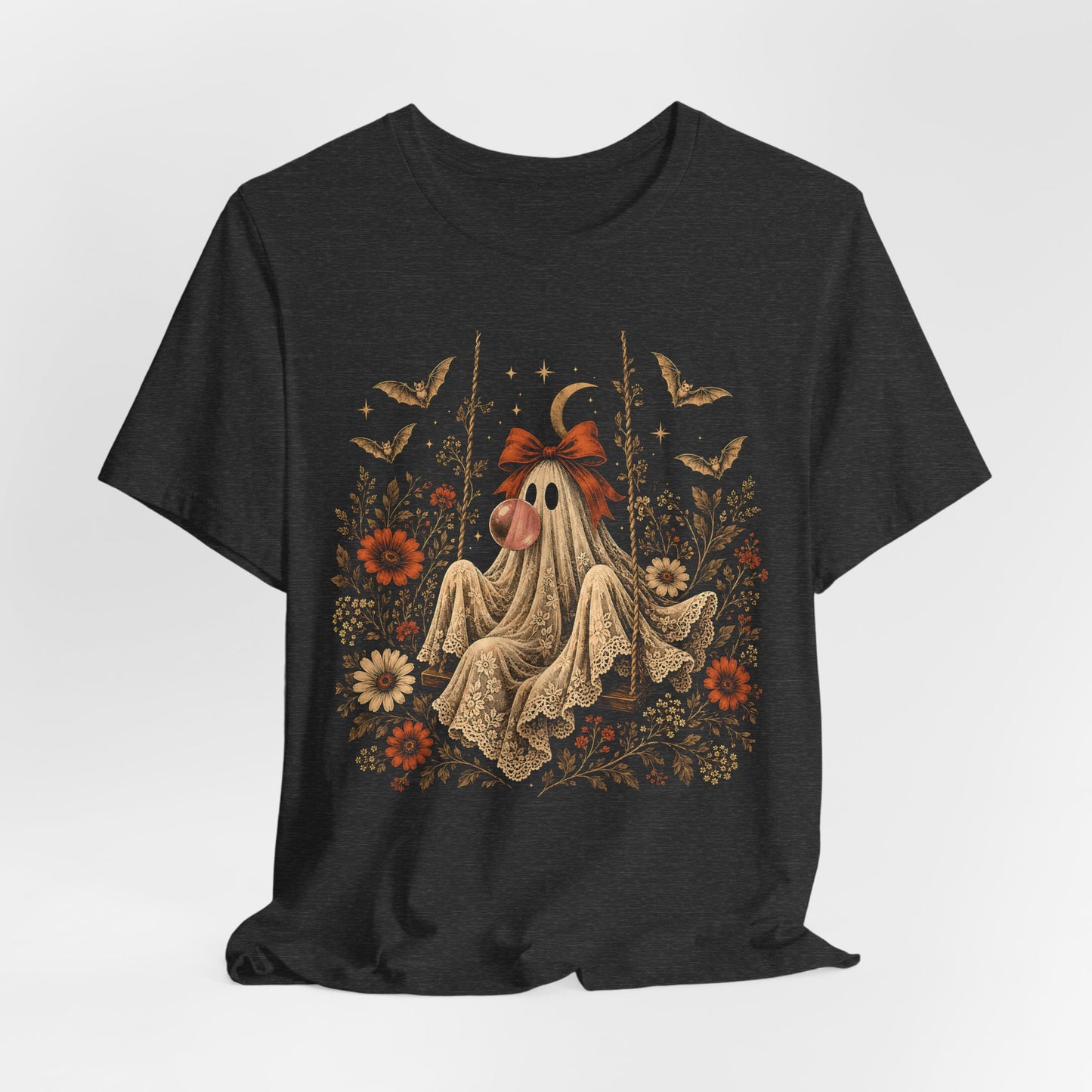 Bubble gum ghost Halloween shirt for women featuring a whimsical ghost sitting on a swing and blowing a bubble. Vintage flowers, botanical elements, bats, lace and a crescent moon surround the character in a playful spooky season design.