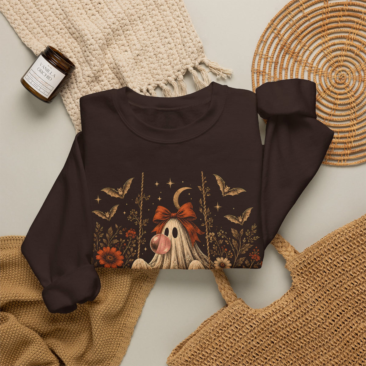 Women's vintage Halloween crewneck sweatshirt featuring a playful ghost on a swing blowing bubble gum. The detailed design combines floral and botanical elements with bats, lace, stars and a crescent moon for a whimsical spooky fall aesthetic.