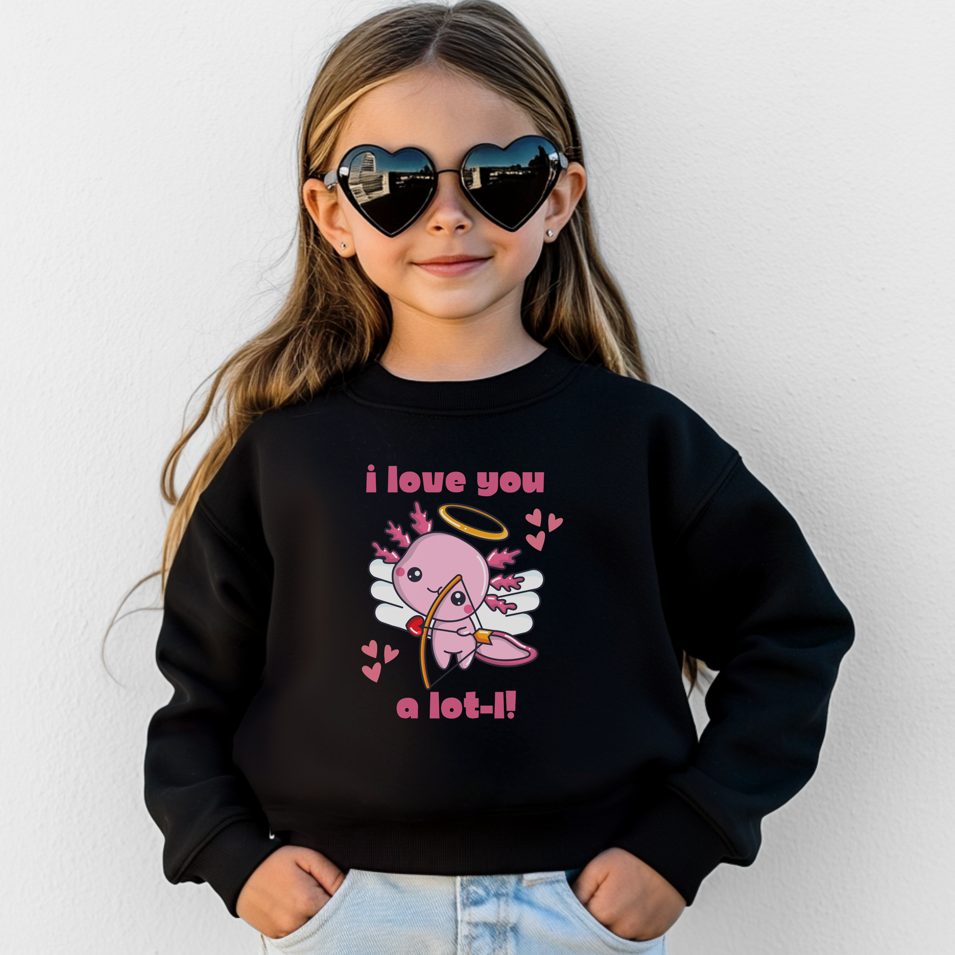 A girl wearing a black youth Valentine sweatshirt showcasing an adorable axolotl cupid illustration with heart accents and the phrase I love you a lot l. The soft fleece crewneck style provides a comfortable fit for everyday wear, school activities, and Valentine celebrations. This cute animal themed sweatshirt is perfect for kids Valentine outfits and matching family apparel.