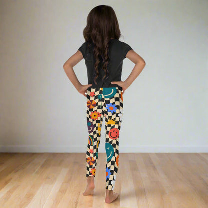 Image: Retro Checkerboard Girls Leggings, in size 2T-7. These toddler and kids yoga pants feature a black and khaki vintage check pattern with smiley faces, daisies, rainbows and suns. These vintage tights make a great birthday present, birthday gift, and are great for back to school, by jaecrece