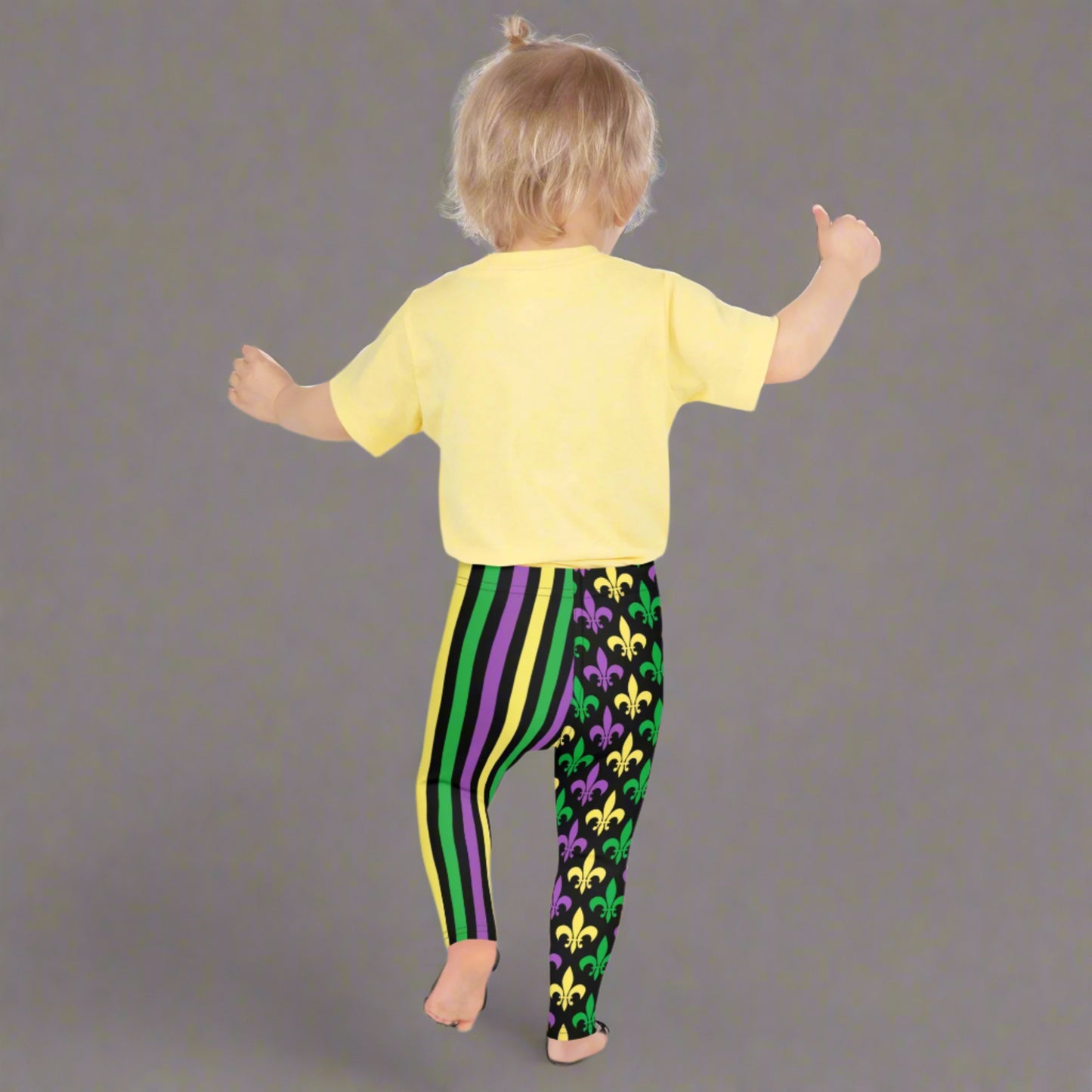 Mardi Gras Stripes and Fleur de Lis Kid's Leggings, size 2T-7. Black leggings featuring a fleur de lis pattern on one leg and vibrant green, purple, and yellow stripes on the other. Perfect for celebrating Mardi Gras, part of a matching collection including leggings for older children and women.