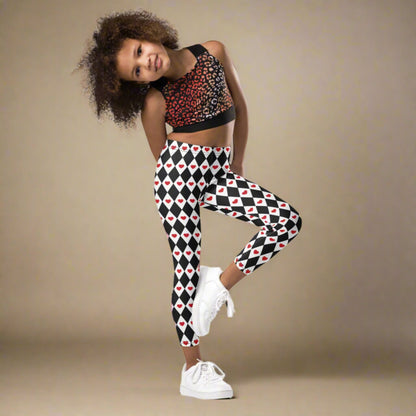 Image: Harlequin Love Girls Leggings in sizes 2T-7. These yoga tights have a black and white checker/ diamond pattern with a red heart accent, the perfect leggings for valentines day or a Queen of Hearts costume, by jaecrece