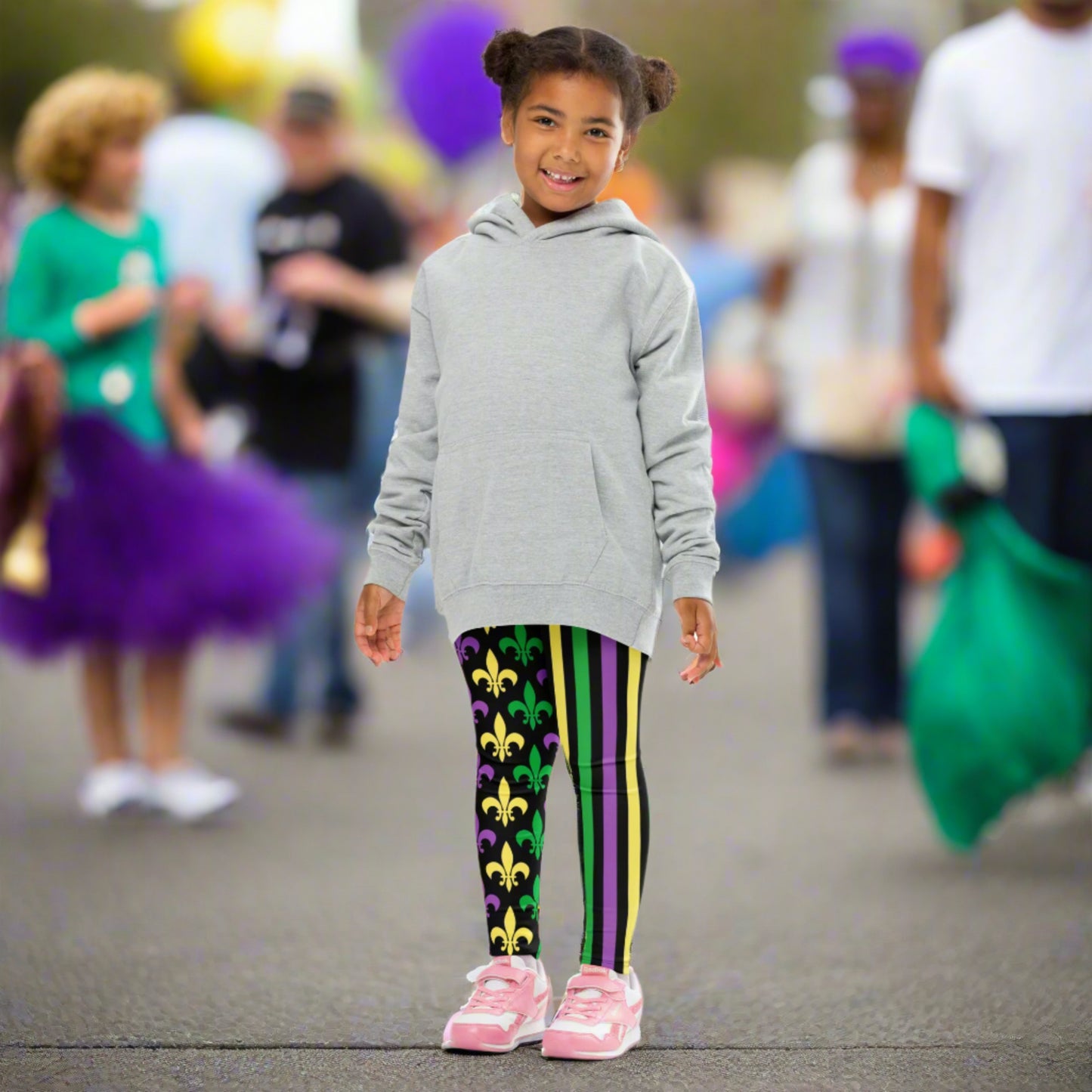 Mardi Gras Stripes and Fleur de Lis Kid's Leggings, size 2T-7. Black leggings featuring a fleur de lis pattern on one leg and vibrant green, purple, and yellow stripes on the other. Perfect for celebrating Mardi Gras, part of a matching collection including leggings for older children and women.