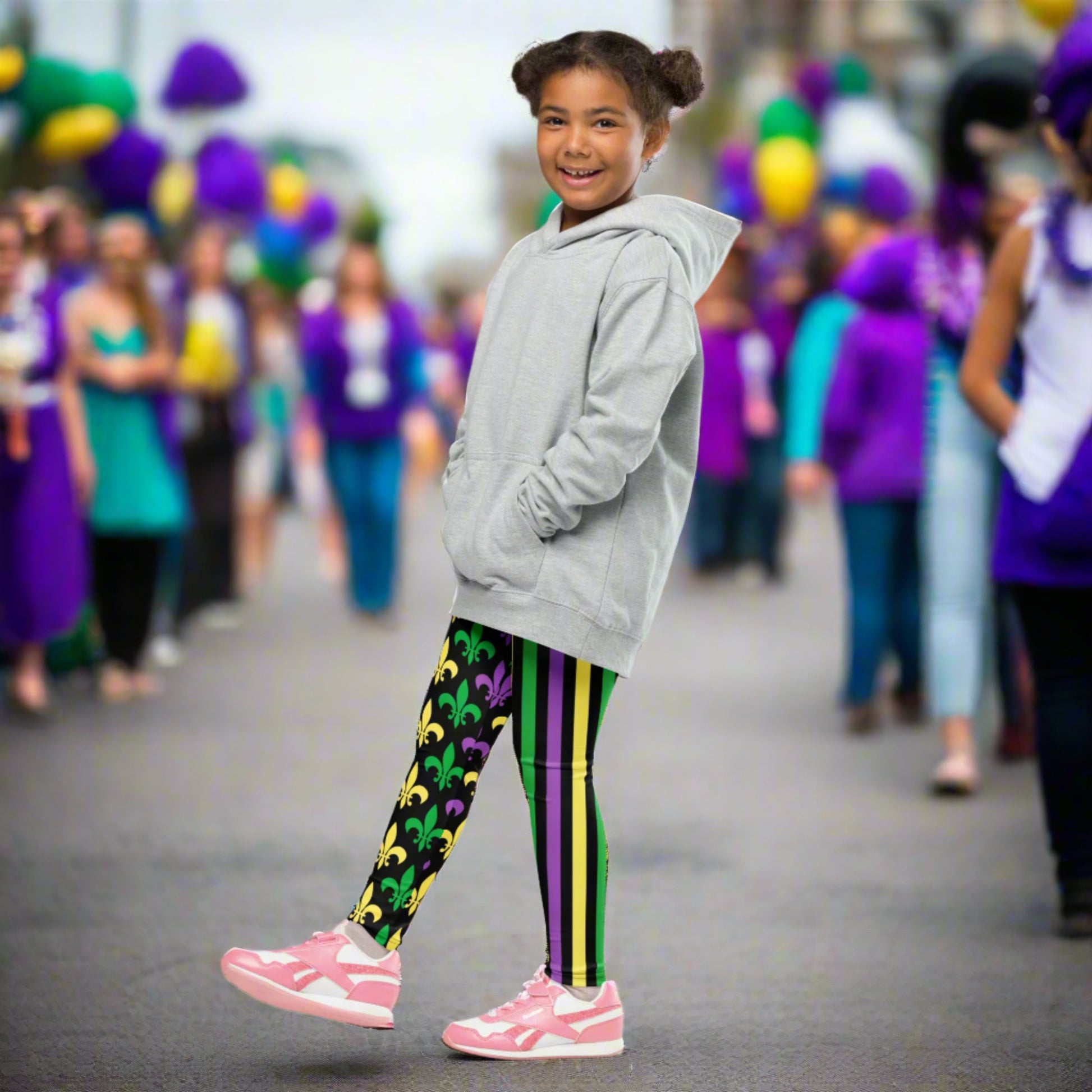 Mardi Gras Stripes and Fleur de Lis Kid's Leggings, size 2T-7. Black leggings featuring a fleur de lis pattern on one leg and vibrant green, purple, and yellow stripes on the other. Perfect for celebrating Mardi Gras, part of a matching collection including leggings for older children and women.