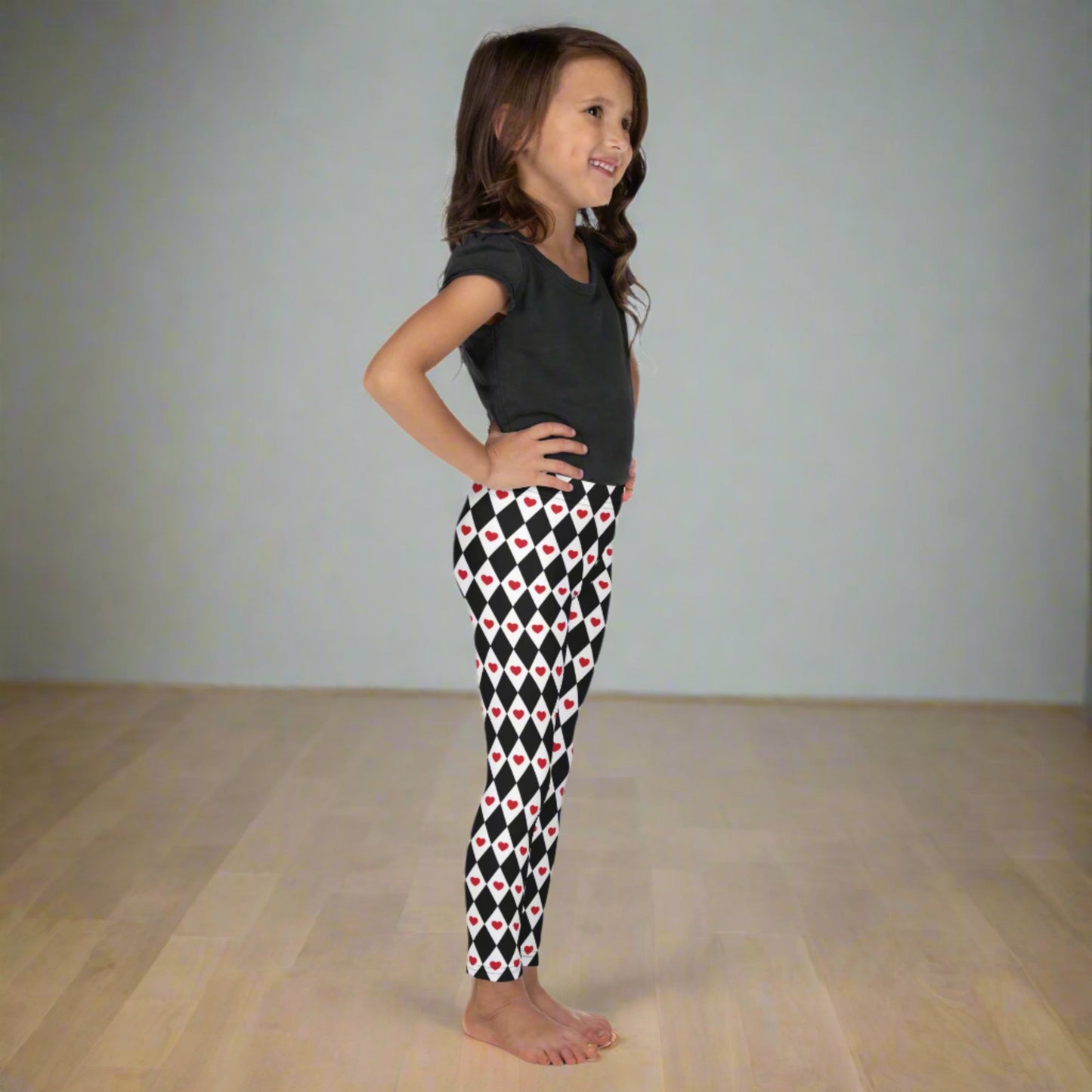 Image: Harlequin Love Girls Leggings in sizes 2T-7. These yoga tights have a black and white checker/ diamond pattern with a red heart accent, the perfect leggings for valentines day or a Queen of Hearts costume, by jaecrece