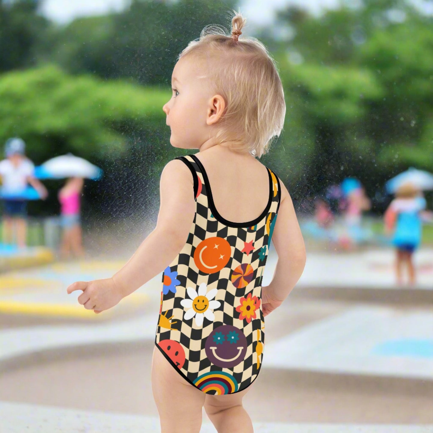 Smiley Face Checkerboard Girls One Piece Bathing Suit. This cute retro swimsuit features a black and khaki checkerboard background, with smiley face, rainbow and daisy graphics. In toddler and girls sizes, 2T-7. by jaecrece.com