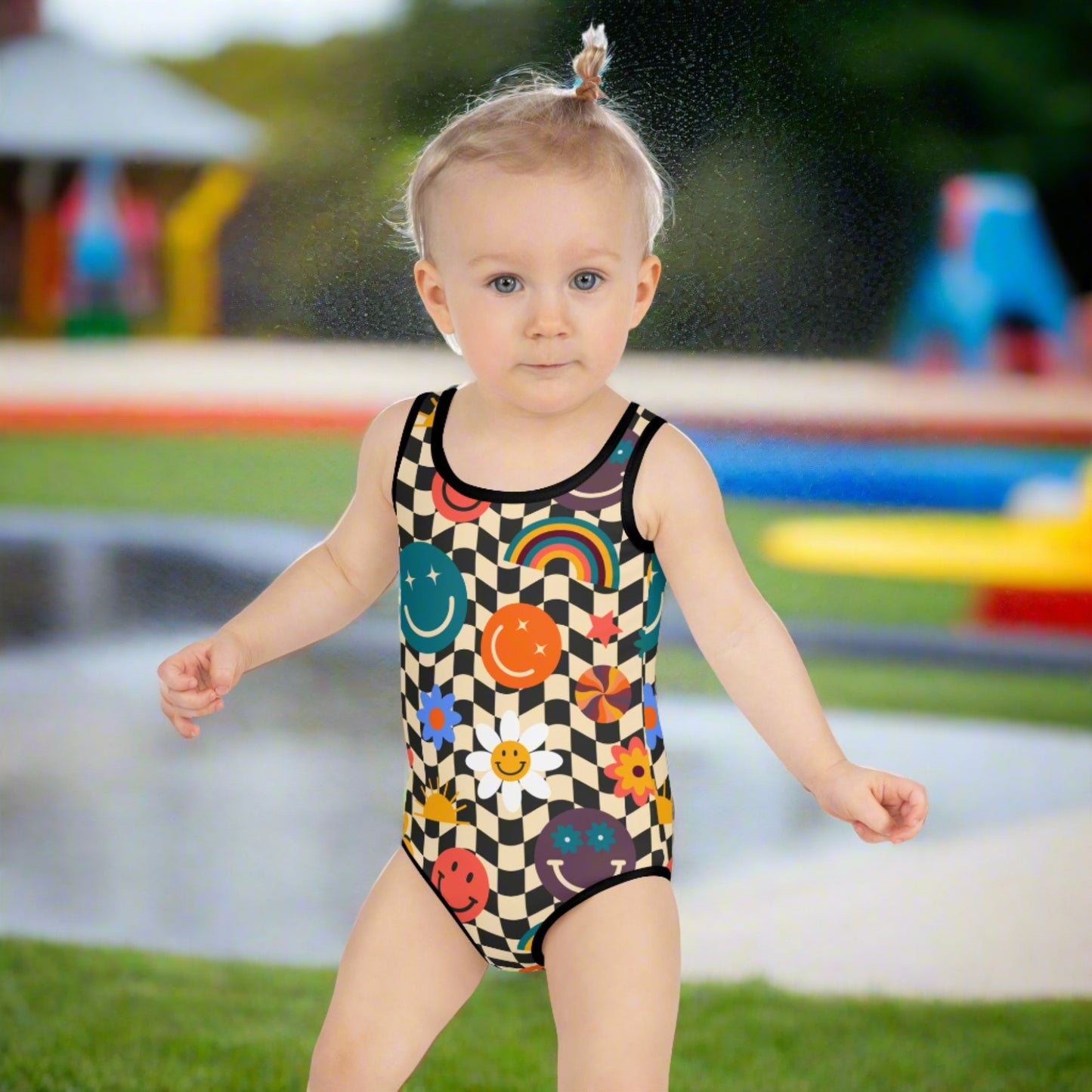 Smiley Face Checkerboard Girls One Piece Bathing Suit. This cute retro swimsuit features a black and khaki checkerboard background, with smiley face, rainbow and daisy graphics. In toddler and girls sizes, 2T-7. by jaecrece.com