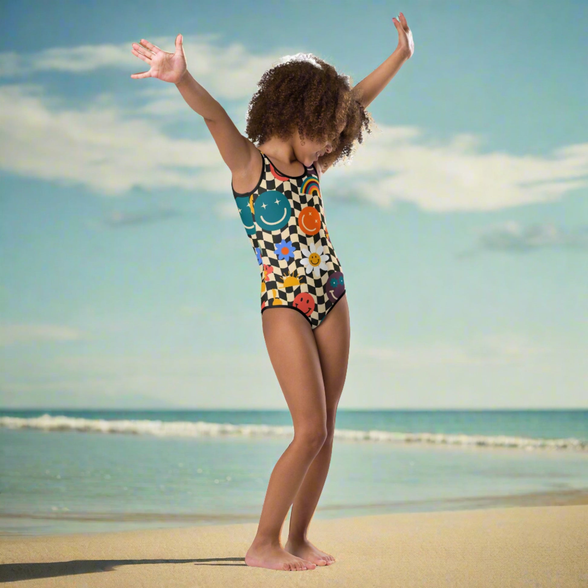 Smiley Face Checkerboard Girls One Piece Bathing Suit. This cute retro swimsuit features a black and khaki checkerboard background, with smiley face, rainbow and daisy graphics. In toddler and girls sizes, 2T-7. by jaecrece.com