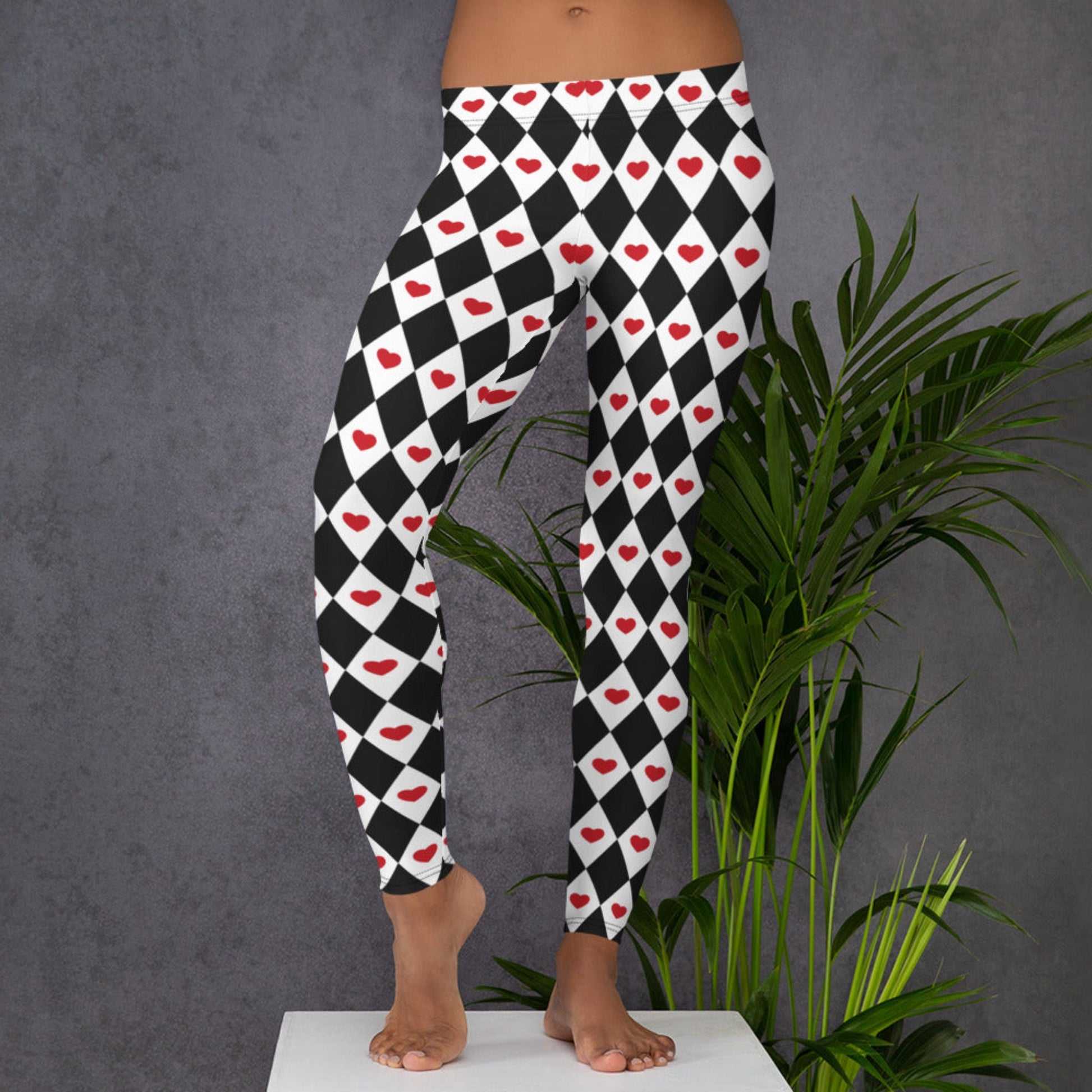 Image: Harlequin Love Ladies Leggings. These yoga tights have a black and white checker/ diamond pattern with a red heart accent, the perfect leggings for valentines day or a Queen of Hearts costume, by jaecrece