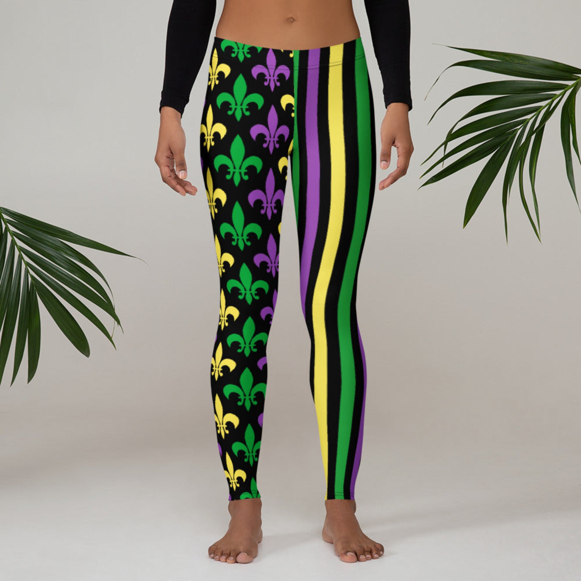 Alt text: Mardi Gras leggings for toddler girls, tweens, and women. Featuring a black background, one leg has bold gold, green, and purple stripes, while the other showcases a fleur-de-lis pattern. Perfect for celebrating New Orleans style with festive flair.