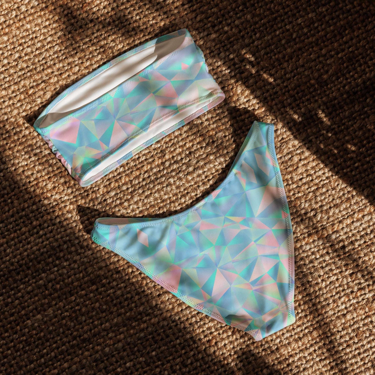 Back view flat lay of the Blue Prisms bandeau bikini featuring a chic V-cut back on the bottoms and seamless style. This two-piece swimsuit combines style, comfort, and sustainability with bold prism colors in blue, pink, and teal. Moisture-wicking and UPF 50+ rated, it's ideal for poolside lounging, ocean swims, or sunny resort getaways. Great for size-inclusive fashion lovers and ethical shoppers.