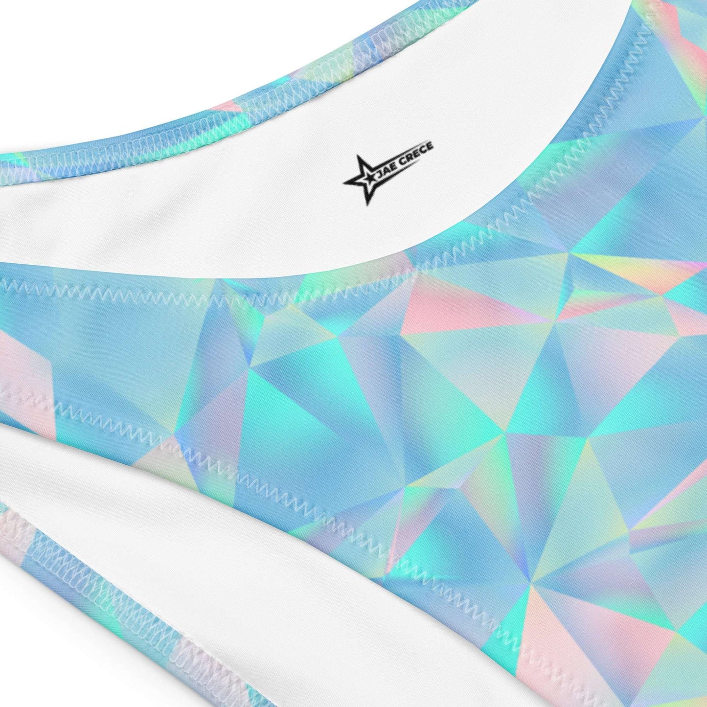  Close up flat lay of the Blue Prisms bandeau bikini, featuring a vibrant geometric prism pattern in blue, teal, and pink. The high-leg V-cut bottoms and seamless strapless top are laid flat to showcase the flattering cut and bold color palette. Made from GRS-certified recycled fabric with four-way stretch and UPF 50+ sun protection. Available in sizes 2XS–6XL, this sustainable swimsuit is ideal for eco-conscious summer style.