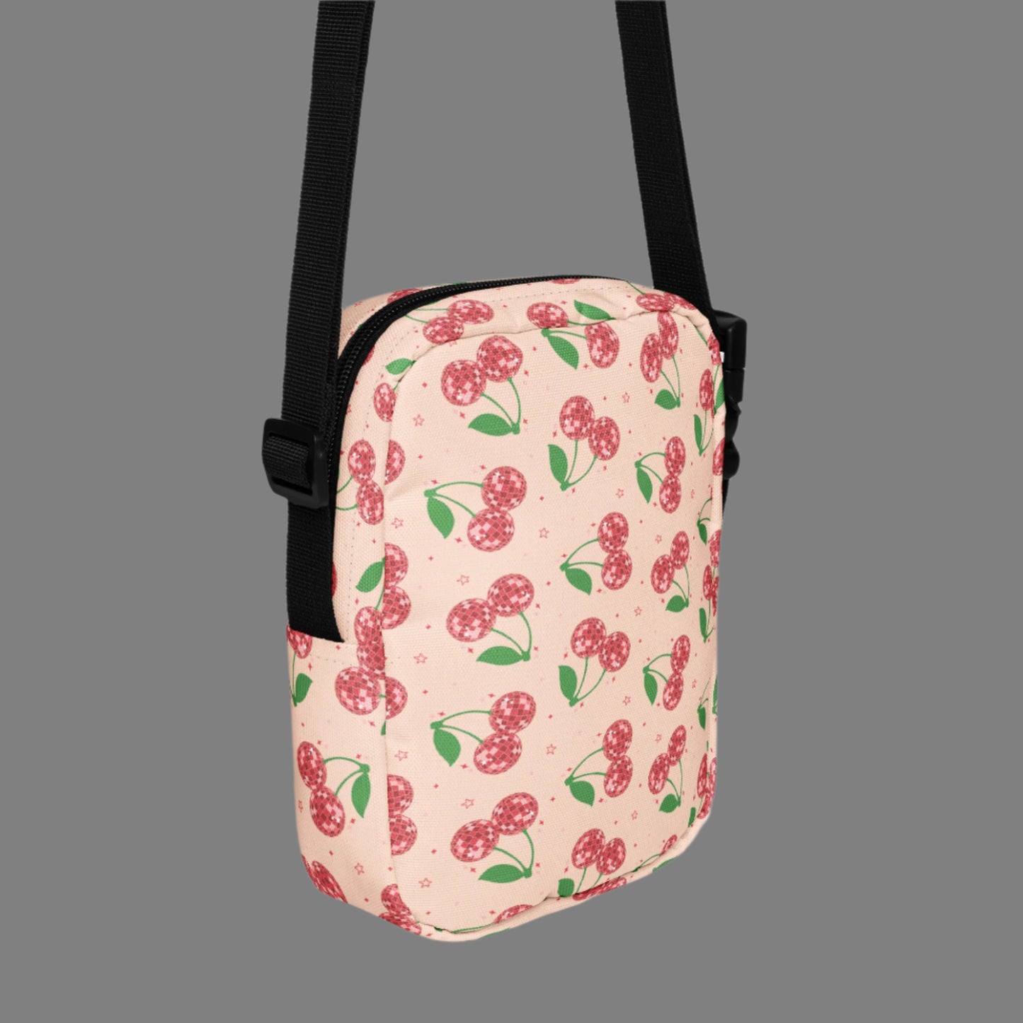 Image: Pink Utility Crossbody bag with a pattern of red disco ball cherries and stars. A great small tote to be worn across the chest, hips, waist. Perfect  as a Valentines Day gift or for outdoor activities, such as parades, hiking or the amusement park, by jaecrece