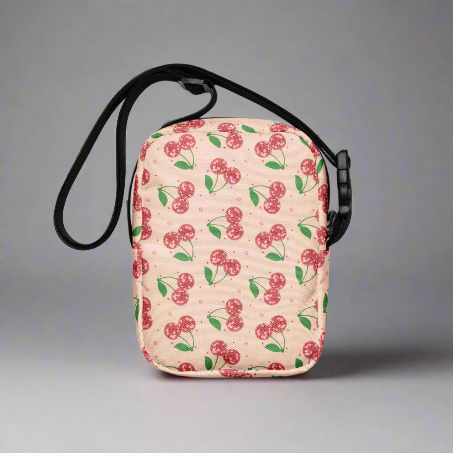 Image: Pink Utility Crossbody bag with a pattern of red disco ball cherries and stars. A great small tote to be worn across the chest, hips, waist. Perfect  as a Valentines Day gift or for outdoor activities, such as parades, hiking or the amusement park, by jaecrece