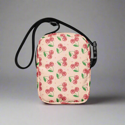 Image: Pink Utility Crossbody bag with a pattern of red disco ball cherries and stars. A great small tote to be worn across the chest, hips, waist. Perfect  as a Valentines Day gift or for outdoor activities, such as parades, hiking or the amusement park, by jaecrece